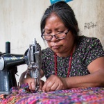 woman wearing reading glasses using sewing machine